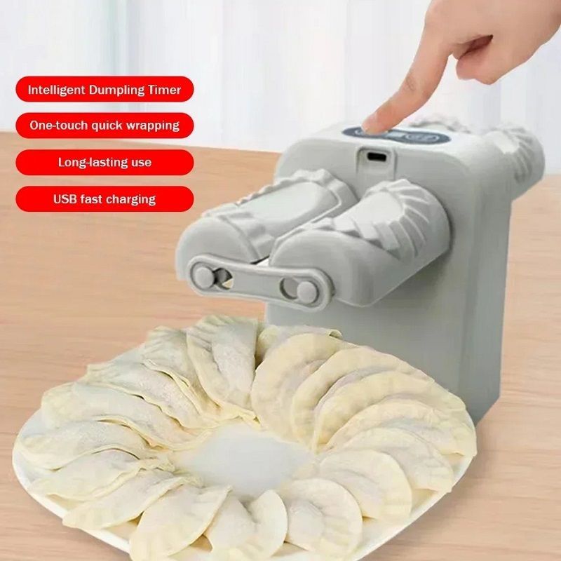 The image shows a person's hand pressing a button on a dumpling maker that is sitting on top of a wooden table. The text on the machine reads "Dumpling Maker" and there is a white curtain in the background.