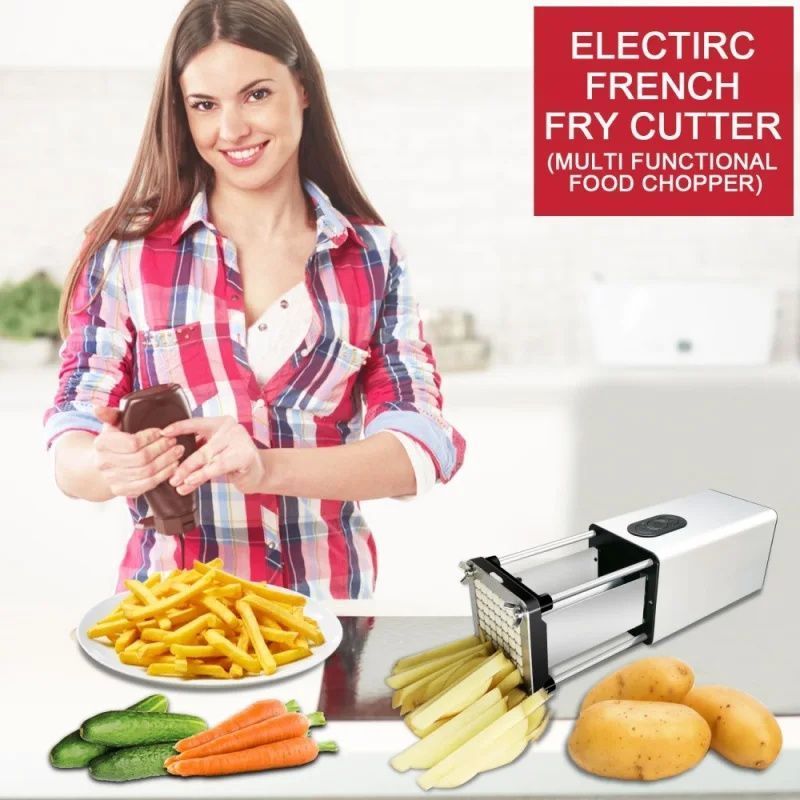 The image shows a woman standing and smiling while holding an electric french fry cutter, which is a multi-functional food chopper. On the table in front of her are a plate of french fries, carrots, and potatoes, as well as other vegetables. In the background, there is a wall with some text on it.