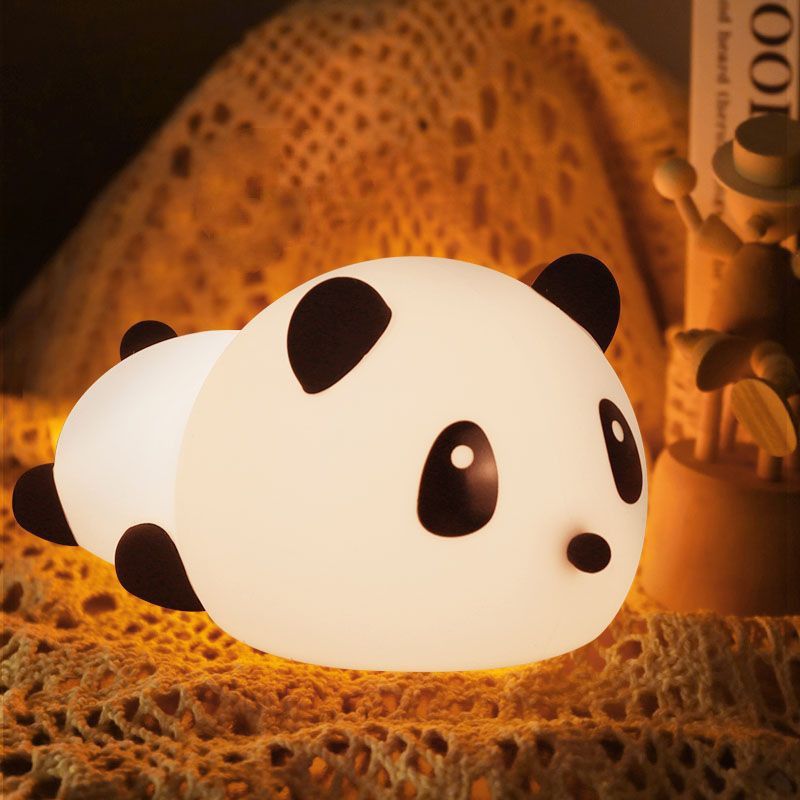 The image shows a panda bear shaped night light sitting on top of a table, with a cloth draped over it. On the right side of the table, there are some objects, and the background is dark.