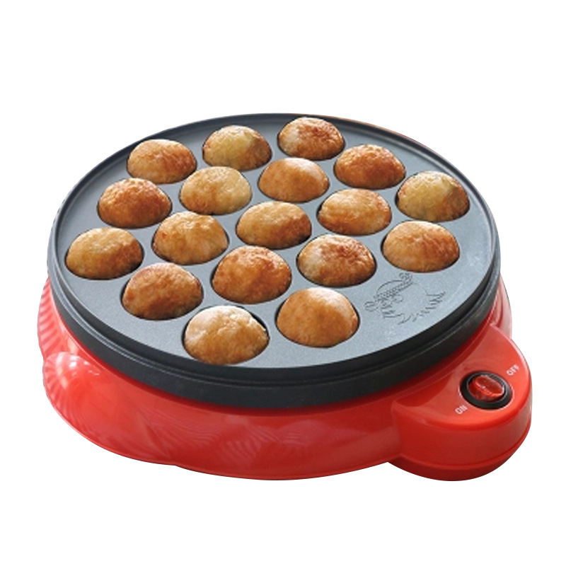 The image shows a round, red-colored muffin pan with a black rim. The pan is filled with small, round, golden-brown muffins. The muffins appear to be freshly baked and are arranged neatly in the pan. There is a small red button on the right side of the pan, likely for adjusting the temperature. The background is white, making the red pan stand out.