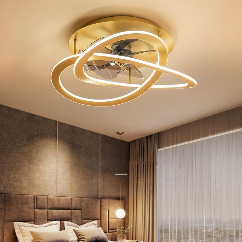 The image shows a modern and luxurious bedroom with a large bed in the center. The bed has a wooden headboard and is covered with white and beige pillows. On the right side of the bed, there is a large window with sheer curtains. Above the bed is a circular ceiling light with a gold finish. The light fixture is made up of three rings that are connected by a thin gold wire. The overall design of the room is elegant and sophisticated.