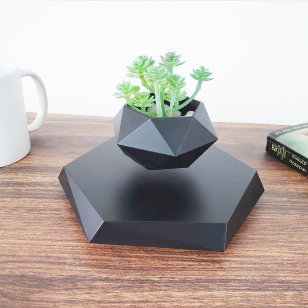 Floating Magnetic Levitating Bonsai Flower Pot Black geometric levitating planter with a green plant above a matching black base.