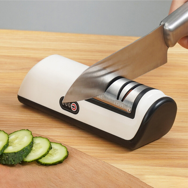 Aura Pro Precision Cordless Electric Knife Sharpener in white showing a chef sharpening a chef knife using the 4-slot silicon carbide wheels.